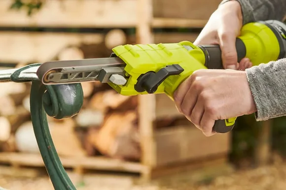 Person schleift Metallgeländer mit Bandschleifer